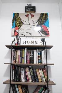 a book shelf with books and a sign that reads home at Beach Inn in Port d'Alcudia