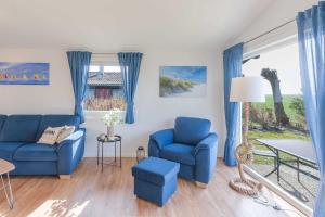 Una sala de estar con sillas azules y una mesa. en Robbys Strandbuex, en Simonsberg