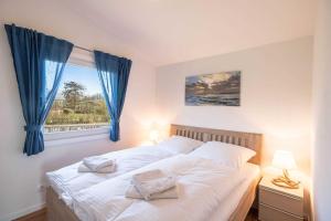 1 dormitorio con 1 cama con cortinas azules y ventana en Robbys Strandbuex, en Simonsberg