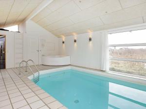 Grønhøjにある10 person holiday home in L kkenのバスルーム(バスタブ、窓付)のスイミングプールを利用できます。