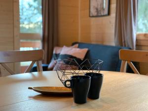 a table with two coffee cups on top of it at Domki nad jeziorem w Burdągu in Jedwabno +4 photos