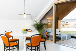 a dining room with a white table and orange chairs at HIMMELBLAU - Design Apartment am Mondsee in Mondsee