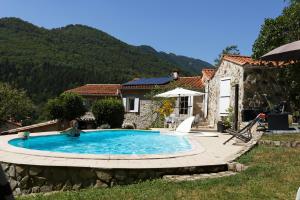 a villa with a swimming pool in front of a house at maison en pierre dans un écrin de verdure in Saint-Laurent-de-Cerdans