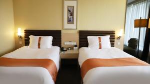 2 camas en una habitación de hotel con 2 camas en Qingdao Parkview Holiday Hotel en Qingdao