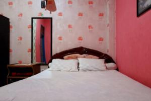 1 dormitorio con 1 cama grande y pared de color rosa en Hotel Rosichan Bau Bau Mitra RedDoorz, en Bau-Bau