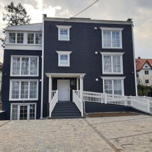 ein schwarzes Haus mit einer weißen Tür und einer Treppe in der Unterkunft Mały Sopot Boutique in Iława