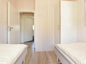 グローセンブローデにあるFour-Bedroom Holiday home in Großenbrode 1の白い壁とウッドフロアの客室で、ベッド2台が備わります。