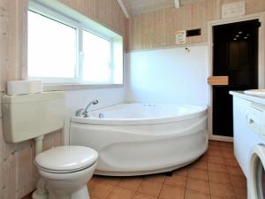 ein Bad mit einer Badewanne, einem WC und einem Fenster in der Unterkunft 6 person holiday home in Otterndorf in Otterndorf
