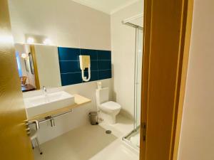 a bathroom with a toilet and a sink and a shower at Quinta das Andorinhas in Carvoeiro