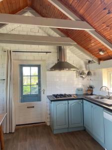 a kitchen with blue cabinets and a window at Waterjuffer in Noordlaren