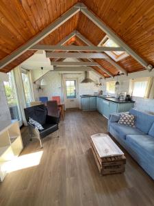 a living room with a blue couch and a kitchen at Waterjuffer in Noordlaren