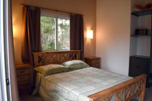 1 dormitorio con cama de madera y ventana en Cabaña Descansos del Este, en Costa del Este
