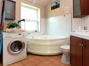 a bathroom with a tub and a washing machine at 12 person holiday home in Otterndorf in Otterndorf