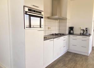 uma cozinha branca com armários brancos e uma janela em Hello Zeeland - Appartement Port Scaldis 09-072 em Breskens