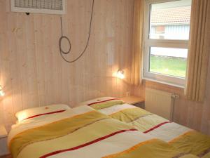 Schlafzimmer mit einem Bett und einem Fenster in der Unterkunft Four-Bedroom Holiday home in Otterndorf 9 in Otterndorf