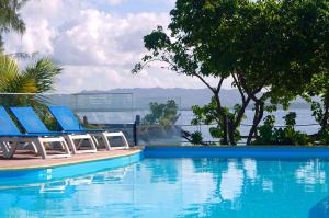 uma piscina com duas espreguiçadeiras junto à água em Carayou Hotel & SPA - Pointe du Bout em Les Trois-Îlets