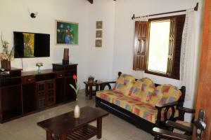 ein Wohnzimmer mit einem Sofa und einem TV in der Unterkunft Hotel Residencial do Mirante in Prado