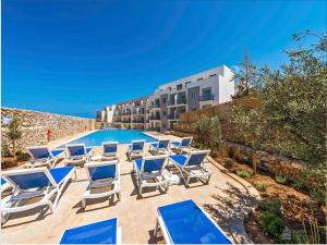 a group of lounge chairs and a swimming pool at Your Room, Your Apartment, Your Shared Pool in Marsalforn