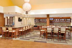 um restaurante com um grande bar com mesas e cadeiras de madeira em Hyatt House LAX Manhattan Beach em El Segundo