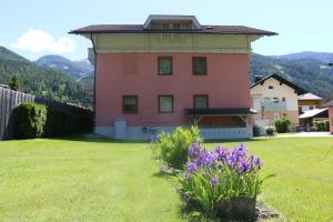 una casa rosa en un patio con flores púrpuras en Haus Elena en Lainach