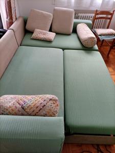 un sofá verde con almohadas en la sala de estar. en Charmant 3 pièces 10 min de Lyon, en Villeurbanne