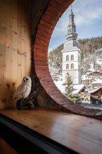 un pequeño pájaro sentado en el alféizar de una ventana con una iglesia en Nouveau et spacieux, Place de l'Eglise et terrasse privative, en La Clusaz