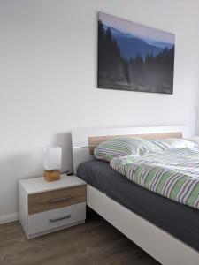 a bedroom with a bed and a nightstand with a picture on the wall at Fernblick Braunlage in Braunlage