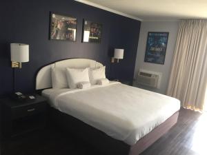 een slaapkamer met een groot bed met witte lakens en kussens bij Hotel Dewey in Dewey Beach