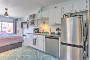 a kitchen with white cabinets and a stainless steel refrigerator at Quaint Studio with Grill 7 Mi to Dtwn Denver! in Aurora