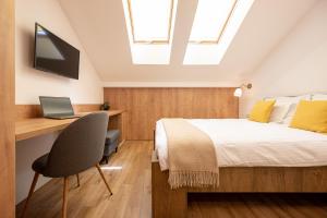 a bedroom with a bed and a desk with a laptop at Central Park Rooms in Oradea