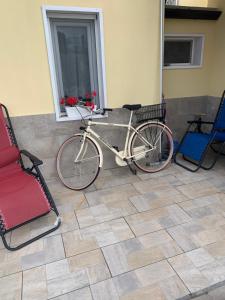 una bicicletta parcheggiata accanto a due sedie e una finestra di Appartamento in villa con piscina a 700m dal mare a Lendinuso