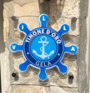 a blue sign on a stone wall with an anchor on it at Timone d’oro in Gela