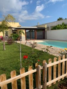 una recinzione di legno di fronte a una casa con piscina di Appartamento in villa con piscina a 700m dal mare a Lendinuso