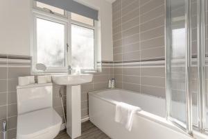 a bathroom with a tub and a sink and a toilet at Modern 2 Bedroom Apartment in Morden in London