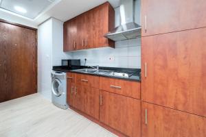 a kitchen with wooden cabinets and a washer and dryer at Stylish and Classy Studio in JLT in Dubai