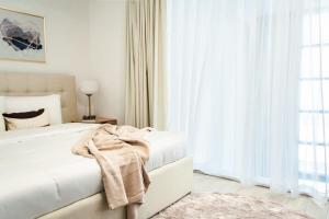 a white bedroom with a bed and a window at Sophisticated 2 Bedroom with Lush Interiors in JVC in Dubai