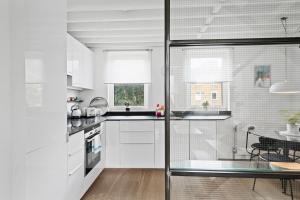 a kitchen with white cabinets and a glass wall at Stylish Modern 2 Bedroom Apartment near Shoreditch in London