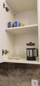 un estante de cocina con cafetera y vasos. en Апартаменты на Греческой en Odesa