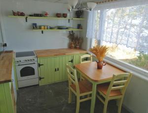 una cocina con armarios verdes, una mesa y una ventana en Karineeme Holiday House, en Mahu