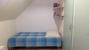 a small room with a bed with a blue blanket at Erdeven - Petite maison de vacances près de la plage de Kerhilio in Erdeven