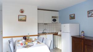 a kitchen with a table and a white refrigerator at Erdeven - Petite maison de vacances près de la plage de Kerhilio in Erdeven