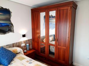 a bedroom with a wooden cabinet next to a bed at Apartamento Playa Riberuca 1 Suances in Suances