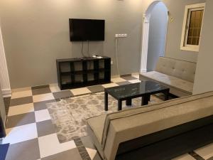 a living room with a couch and a tv at Economic Homes Apartments in Yanbu
