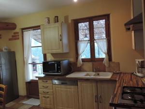 a kitchen with a microwave and a sink at 22 aout au 12 sept loc 2 ch, clim, piscine 11 x 5 vue Luberon in Cavaillon