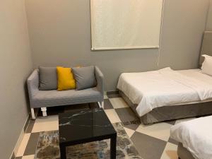 a bedroom with a bed and a chair and a table at Economic Homes Apartments in Yanbu
