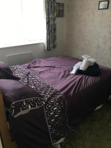 een slaapkamer met een bed met paarse lakens en een raam bij Little Trains of Dartmouth in Dartmouth