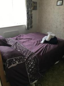 a bedroom with a bed with purple sheets and a window at Little Trains of Dartmouth in Dartmouth