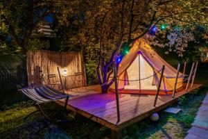 uma tenda e uma rede de descanso num deque de madeira em Dragonfly Gardens Urban Glamping Brasov em Brasov