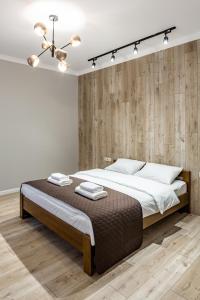 ein Schlafzimmer mit einem großen Bett und einer Holzwand in der Unterkunft Rynok Square Apartments in Lwiw