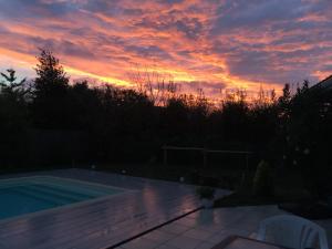una puesta de sol sobre una piscina en un patio en Le Teich Tranquille, en Le Teich